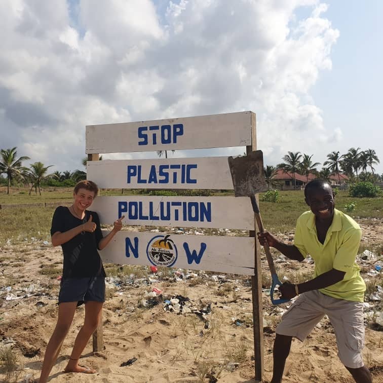 EIn Foto von der kulturweit-Freiwilligen und einer weiteren Person neben einem großen Schild mit der Aufschrift "Stop Plastic Pollution NW". 