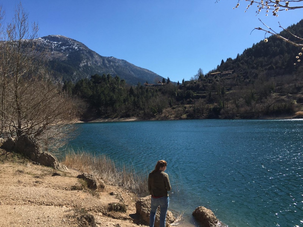 Ein Foto von der kulturweit-Freiwilligen vor einem blauen Gewässer, das von einer Berglandschaft umgeben ist. 