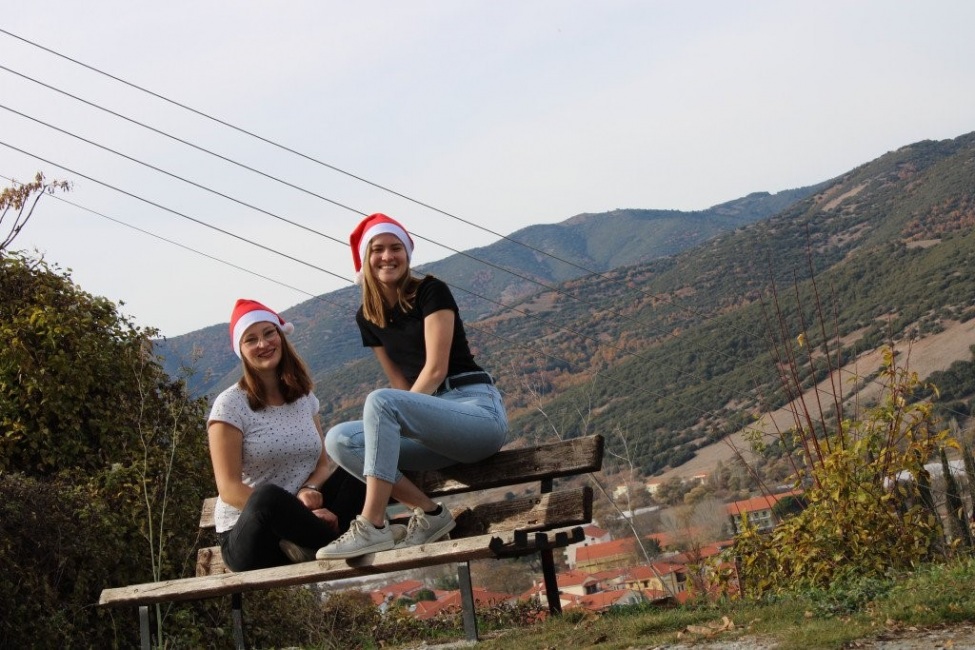 Ein Foto von den beiden kulturweit-Freiwilligen mit einer Weihnachtsmann-Mütze vor einer Berglandschaft.