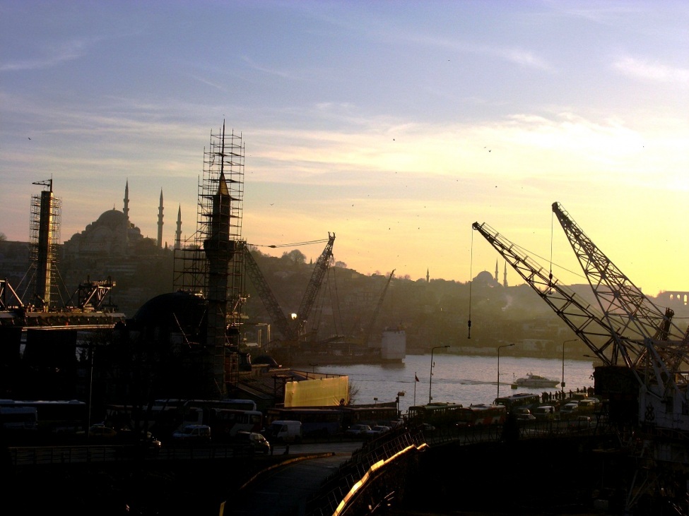 Ein Foto von Istanbul bei Sonnenauf- oder Untergang. Im Vordergrund ragen die Krähne in die Höhe.