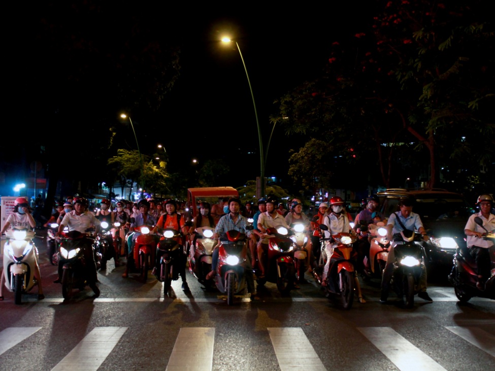 Ein Foto von einer Gruppe von Motarradfahrer*innen auf einer dunklen Straße.