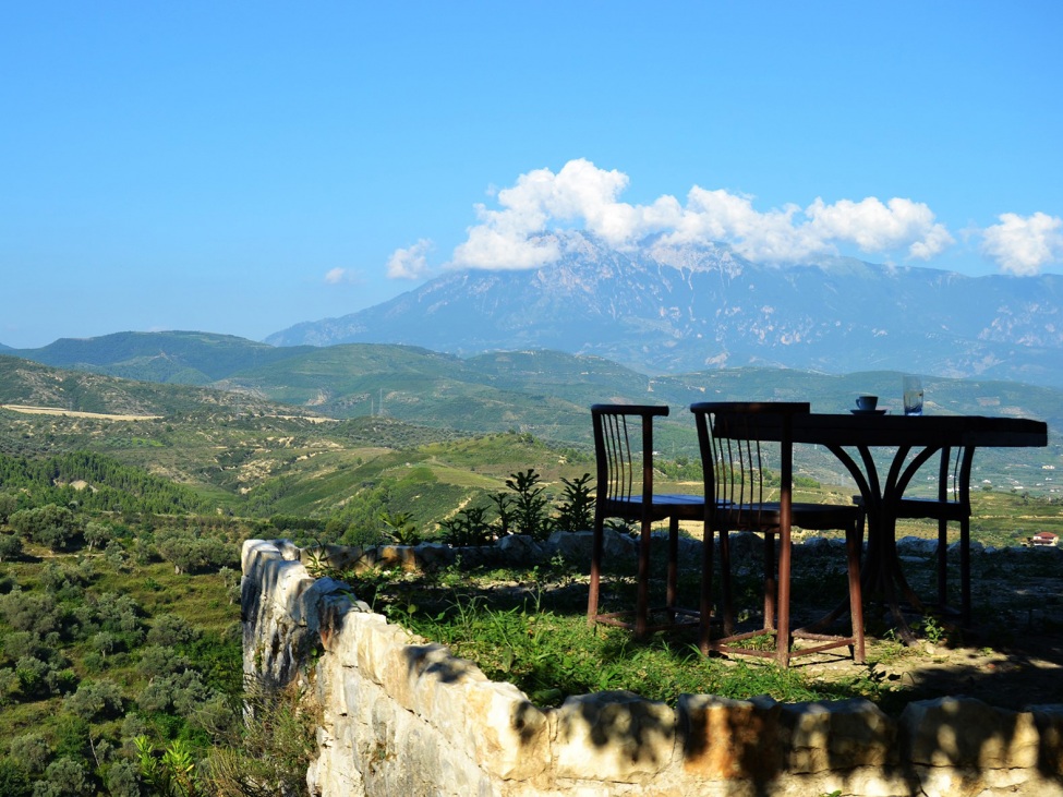 Ein Foto von einer Terrasse mit Tisch und Stühlen inmitten einer Berglandschaft.