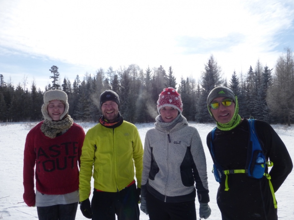 Ein Foto von einer Gruppe von vier jungen Erwachsenen in einer sonnigen Schneelandschaft.