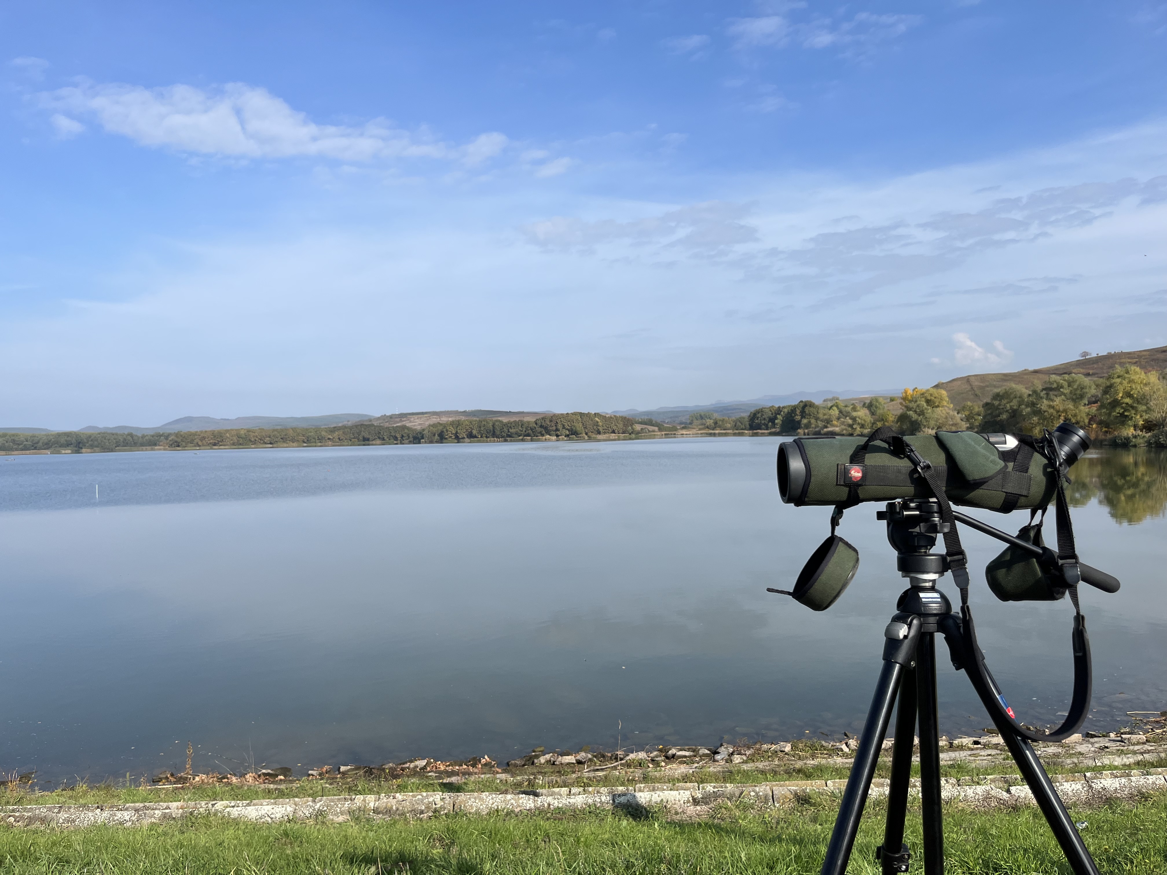 Ein Fernglas auf Stativ steht vor einem See