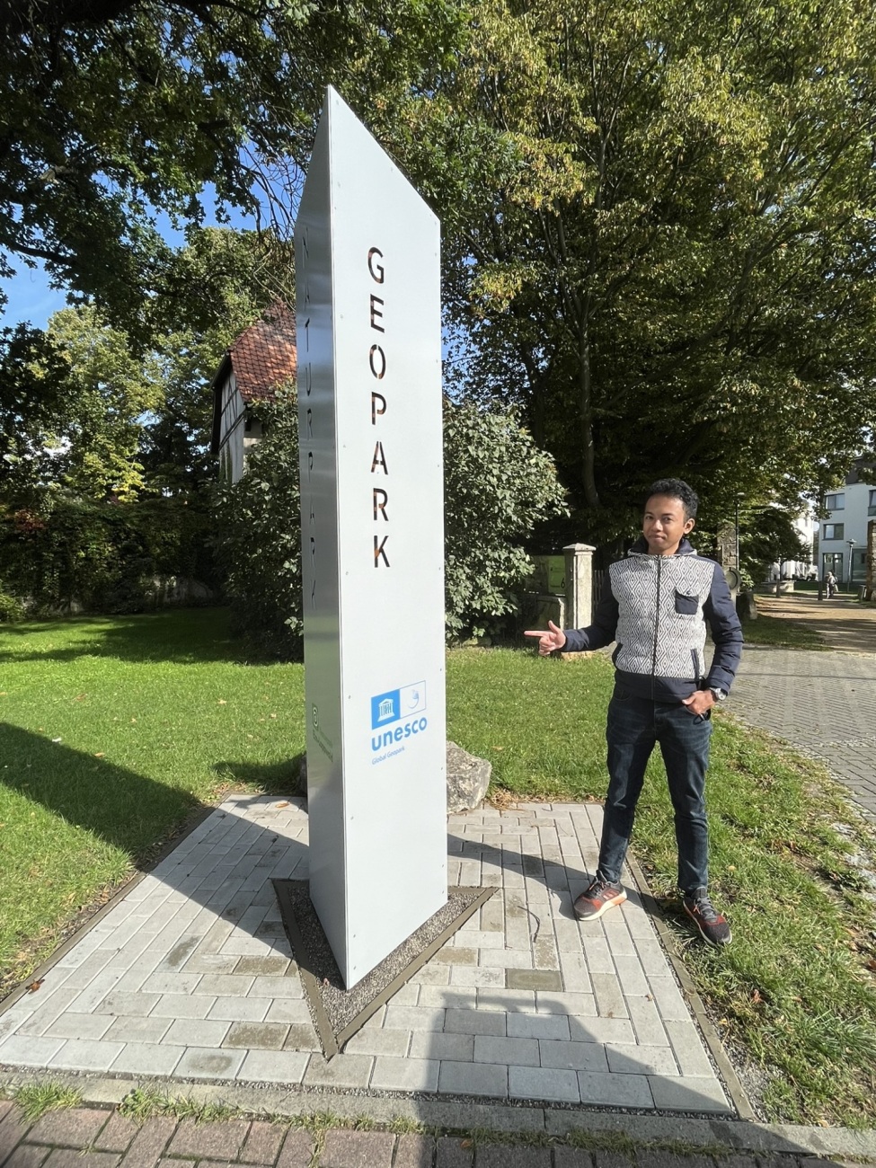 Luciano steht neben dem Schild des Geoparks Harz