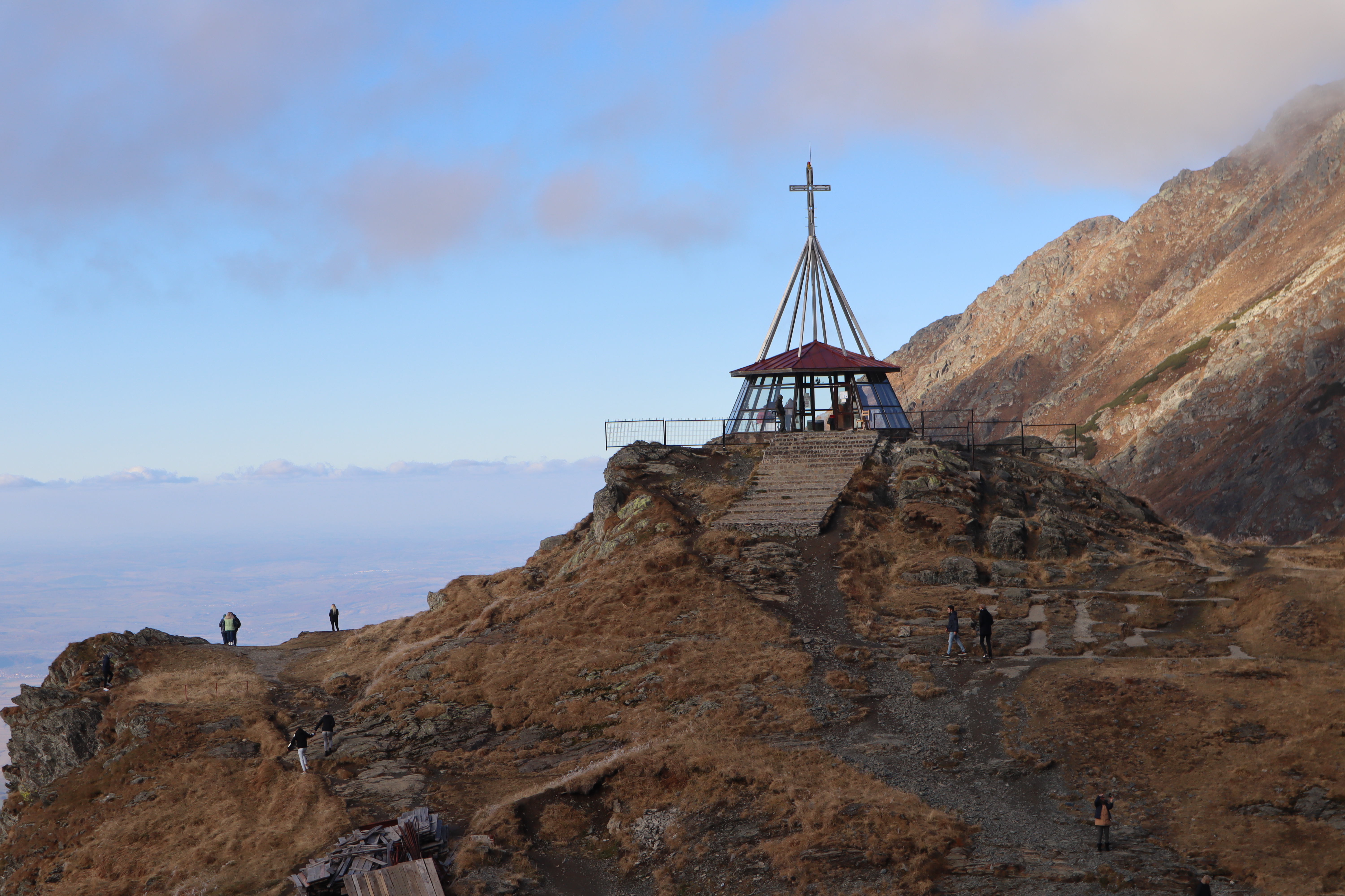 Eine Bergspitze mit Gipfelkreuz und einigen Personen