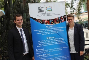 Inken und Chris stehen neben einem Banner der Nationakommission