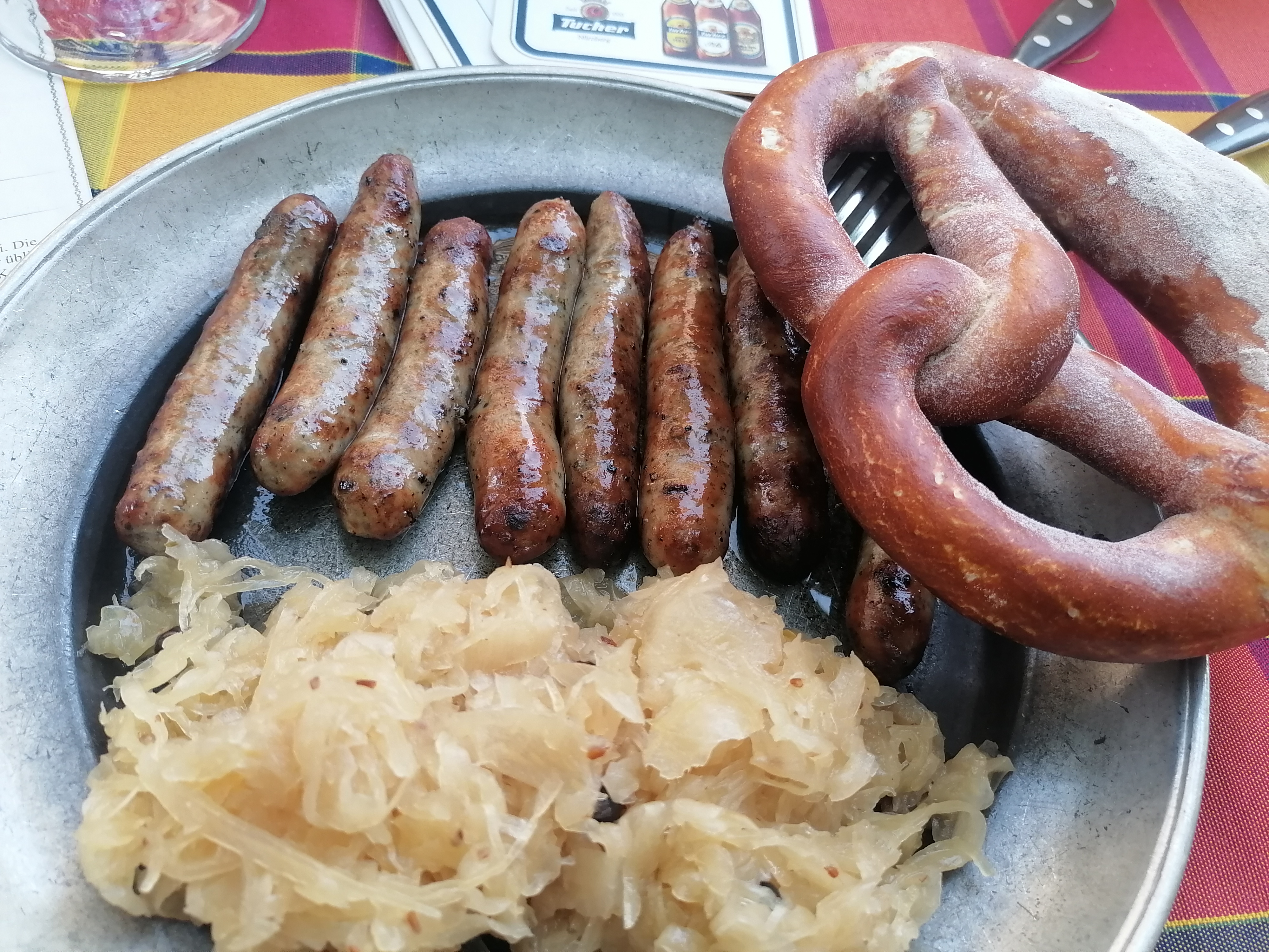 Ein Teller mit Bratwürsten, Brezel und Sauerkraut.