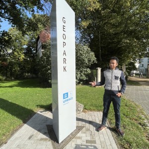 Luciano steht neben dem Schild des Geoparks Harz